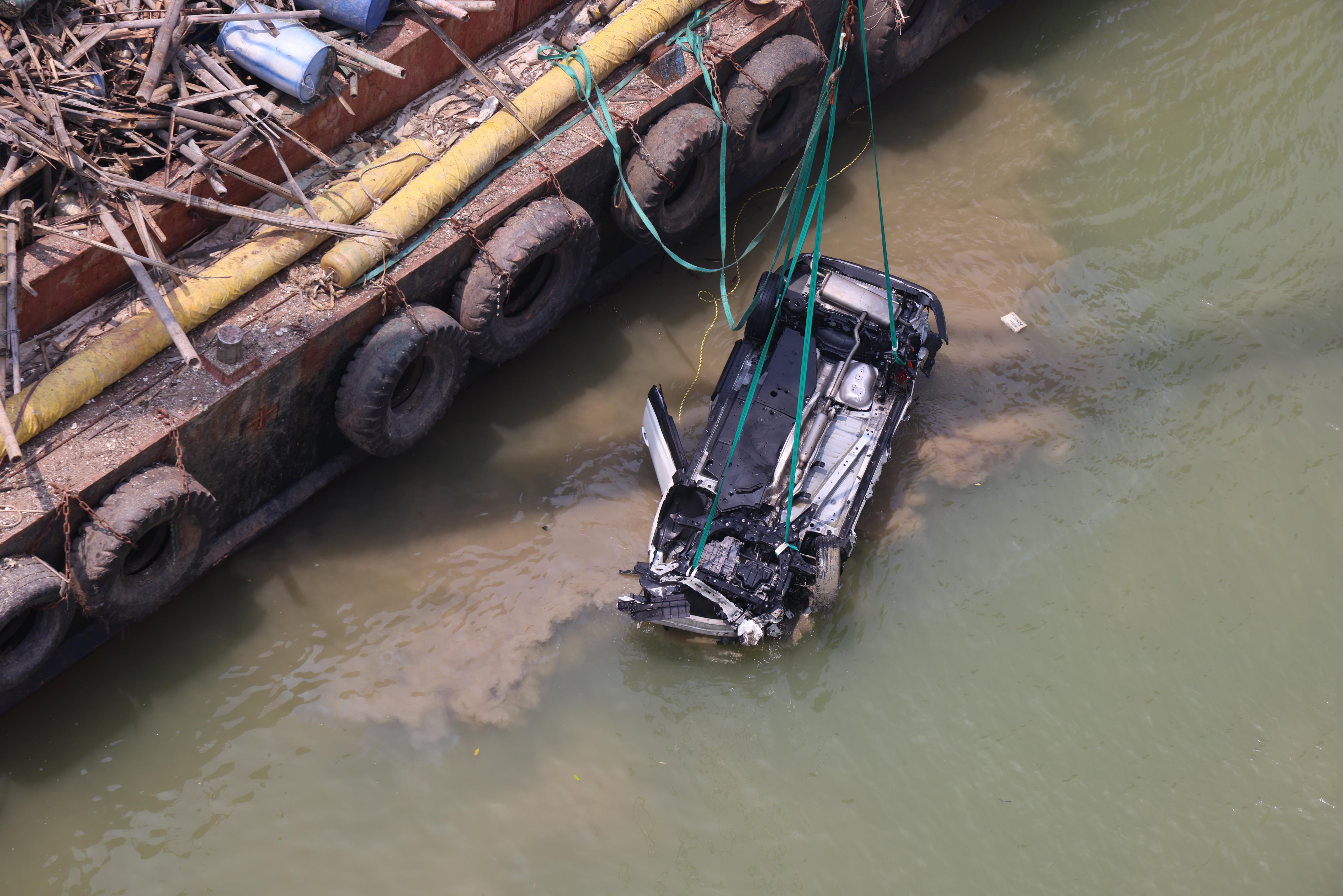 吊臂躉船在大橋附近的位置,用鋼纜把私家車由海中吊起,放上躉船運走。