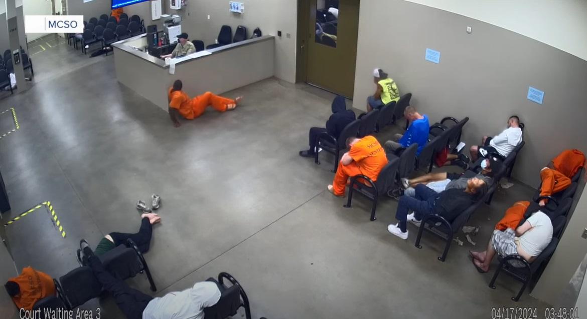 男囚犯在獄警櫃台前忍者式爬行,在場其他人不理會。(互聯網)