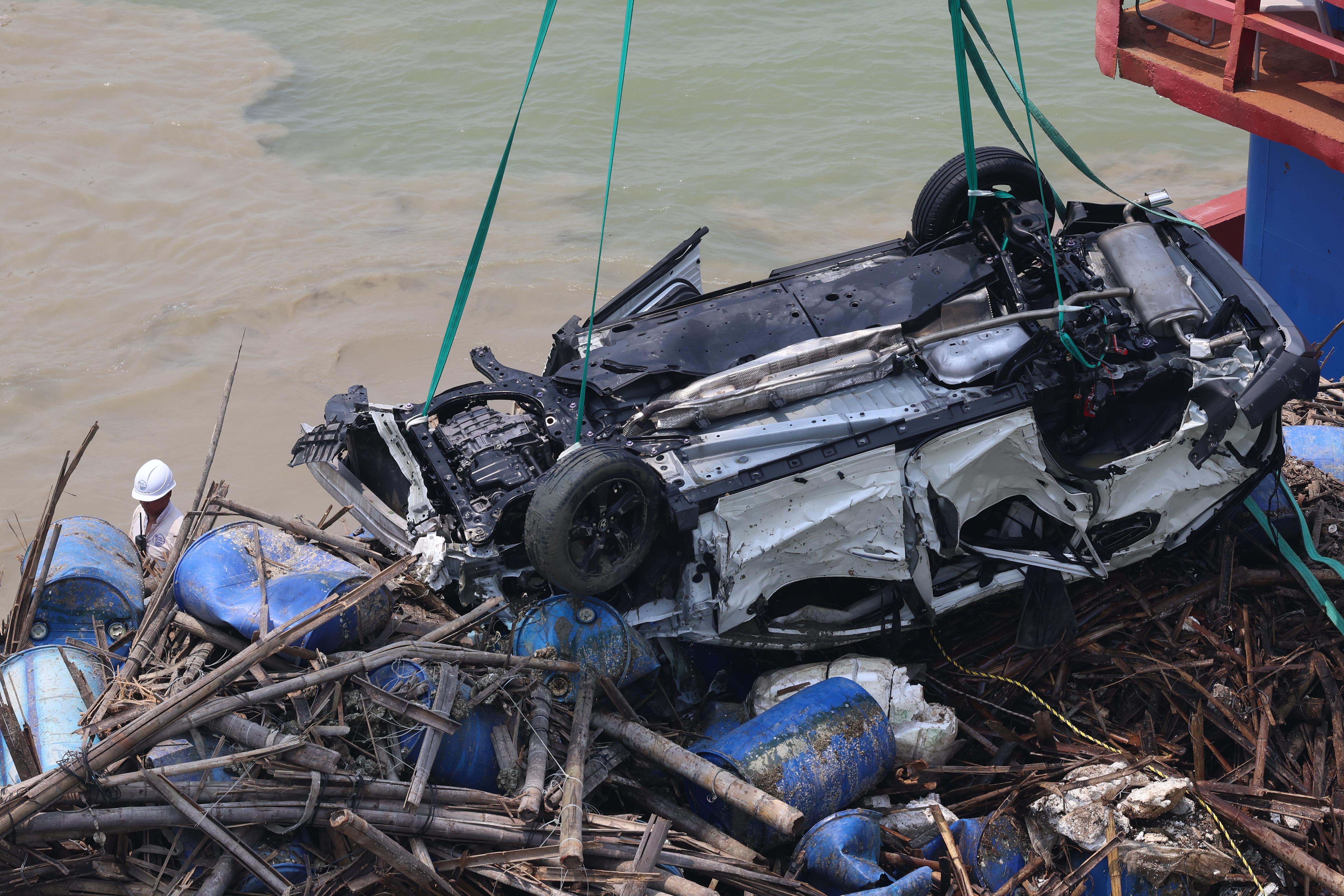 吊臂躉船在大橋附近的位置,用鋼纜把私家車由海中吊起,放上躉船運走。