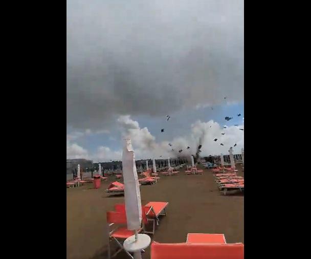 巨大水龍捲把太陽傘和沙灘椅等捲上半空。(互聯網)