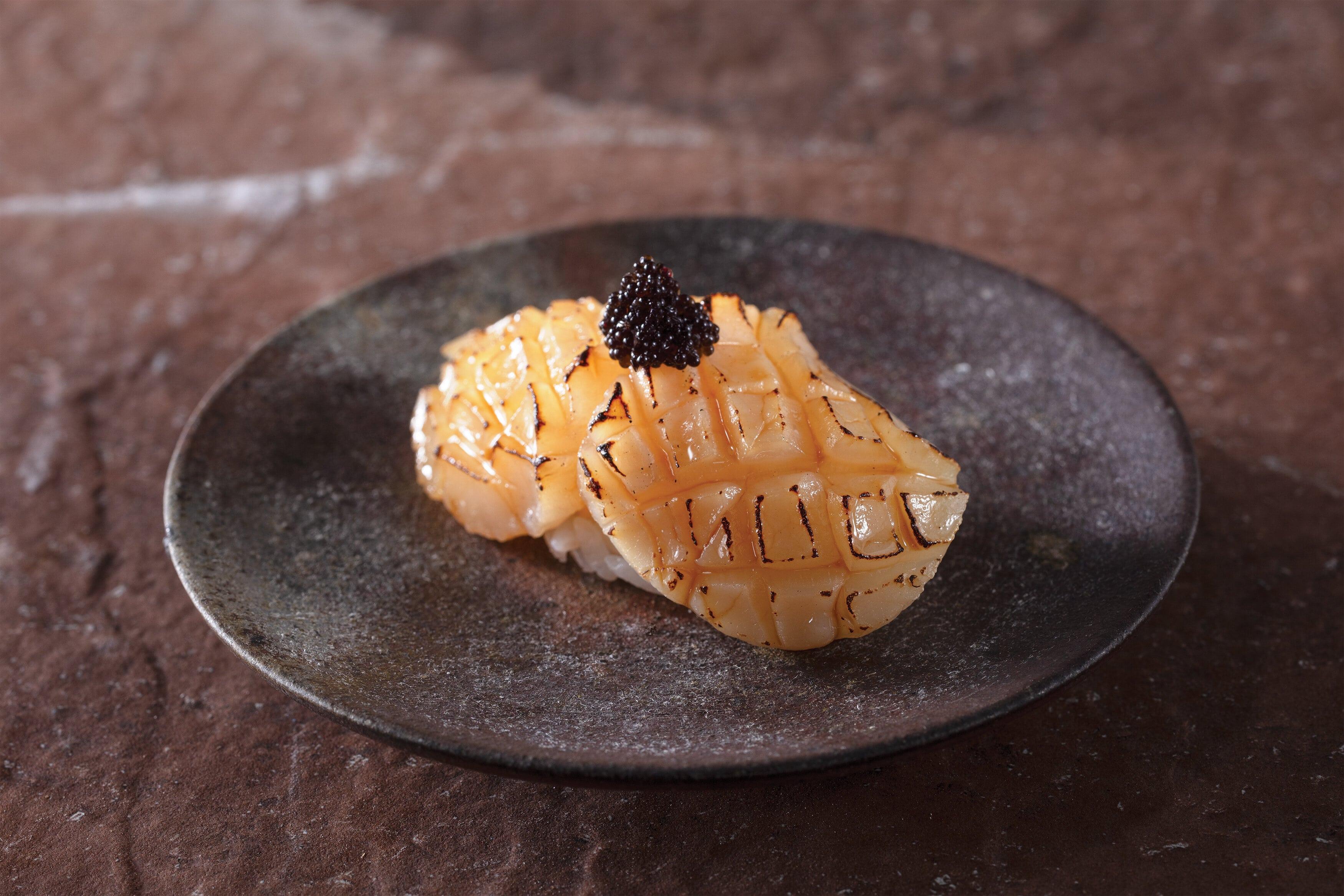 炙燒北海道產活帆立貝壽司 $32件 將帆立貝切成格仔紋,塗上琉球醬油,輕輕炙燒,放上鹹香黑魚籽,味道與口感均具層次感。