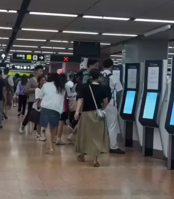 一名長裙女大搖大擺手持香煙,步入港鐵旺角站大堂「買飛」,雖未有吸食,但疑已燃點。(影片截圖)