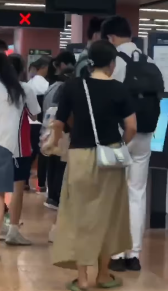 一名長裙女大搖大擺手持香煙,步入港鐵旺角站大堂「買飛」,雖未有吸食,但疑已燃點。(影片截圖)