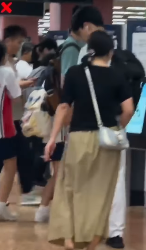 一名長裙女大搖大擺手持香煙,步入港鐵旺角站大堂「買飛」,雖未有吸食,但疑已燃點。(影片截圖)