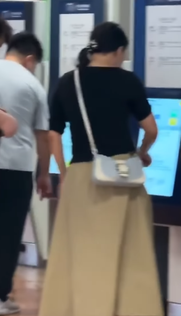 一名長裙女大搖大擺手持香煙,步入港鐵旺角站大堂「買飛」,雖未有吸食,但疑已燃點。(影片截圖)