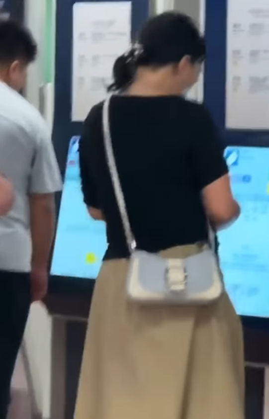 一名長裙女大搖大擺手持香煙,步入港鐵旺角站大堂「買飛」,雖未有吸食,但疑已燃點。(影片截圖)