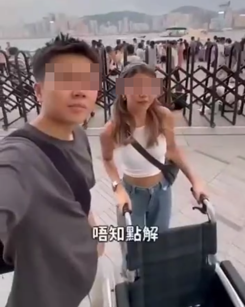 兩名香港網紅稱對很多遊客來到「踎低」感到不解,嘲諷他們是否腰骨有問題,手推輪椅往尖沙咀星光大道用普通話詢問多名蹲在地上的遊客:「我看你蹲了好久,是不是腰骨有問題,要不要坐輪椅?」(影片截圖)