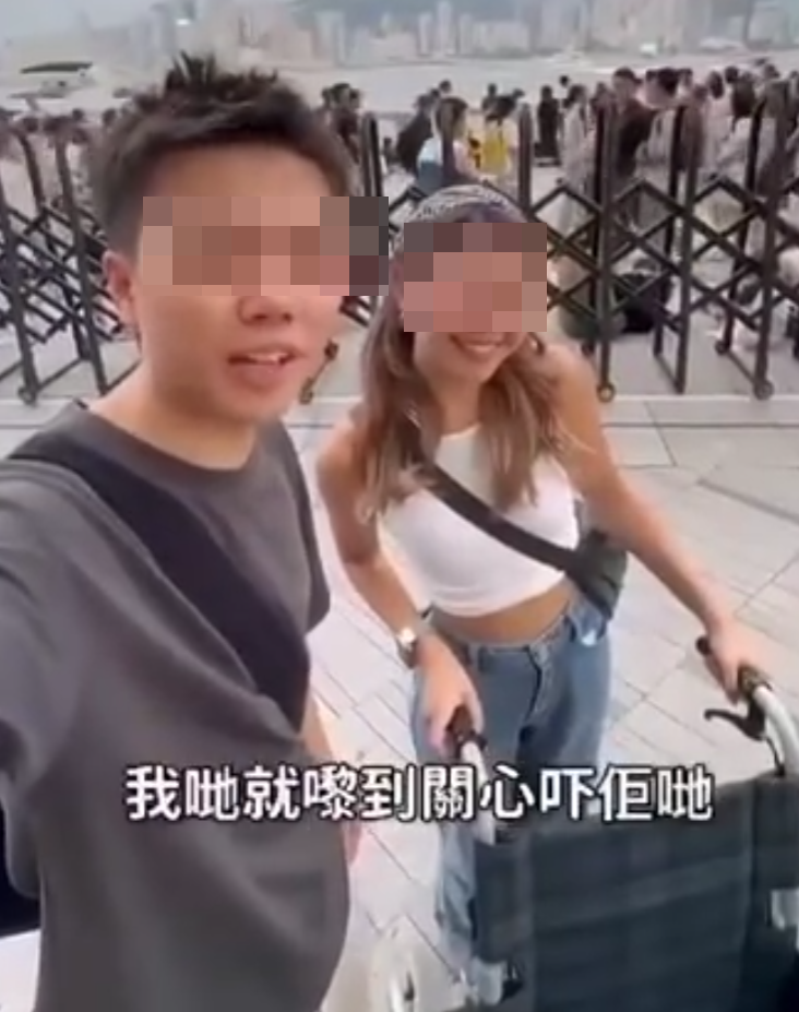 兩名香港網紅稱對很多遊客來到「踎低」感到不解,嘲諷他們是否腰骨有問題,手推輪椅往尖沙咀星光大道用普通話詢問多名蹲在地上的遊客:「我看你蹲了好久,是不是腰骨有問題,要不要坐輪椅?」(影片截圖)