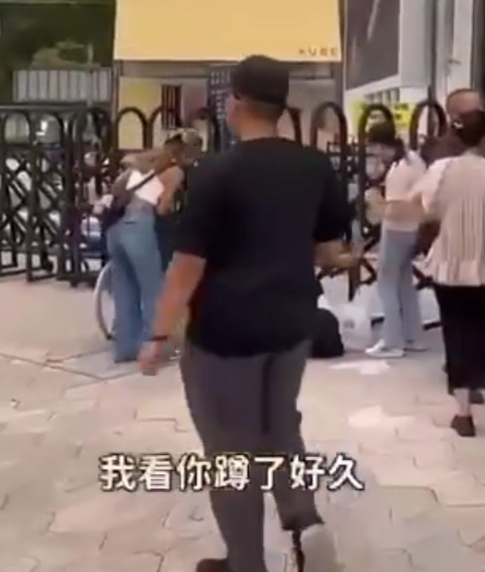 兩名香港網紅稱對很多遊客來到「踎低」感到不解,嘲諷他們是否腰骨有問題,手推輪椅往尖沙咀星光大道用普通話詢問多名蹲在地上的遊客:「我看你蹲了好久,是不是腰骨有問題,要不要坐輪椅?」(影片截圖)