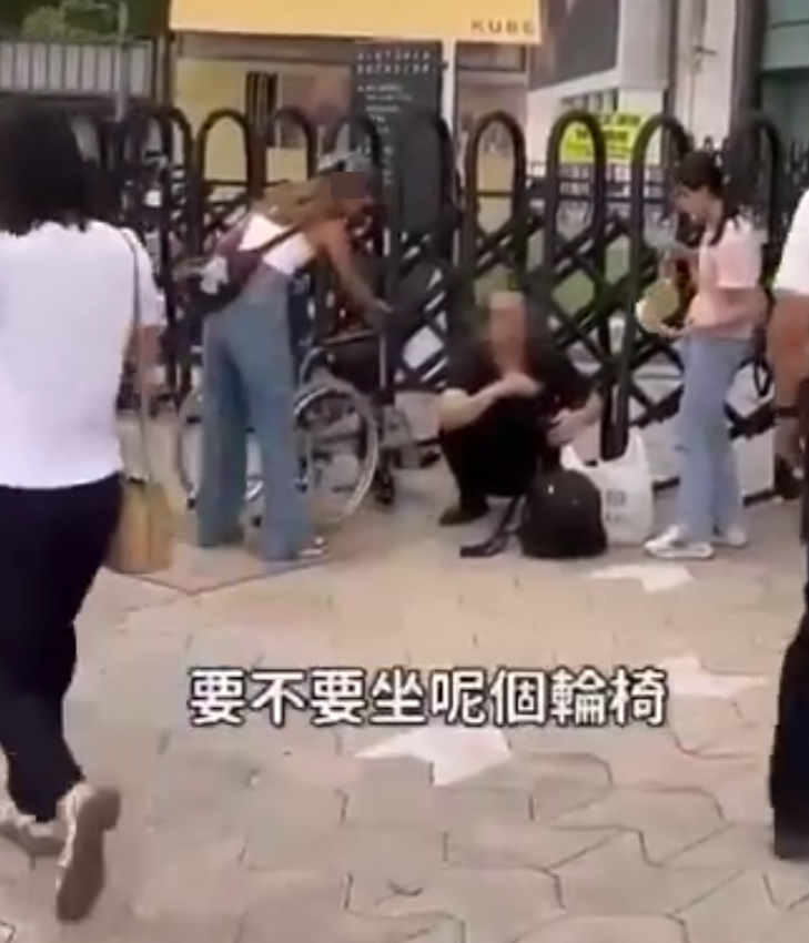 兩名香港網紅稱對很多遊客來到「踎低」感到不解,嘲諷他們是否腰骨有問題,手推輪椅往尖沙咀星光大道用普通話詢問多名蹲在地上的遊客:「我看你蹲了好久,是不是腰骨有問題,要不要坐輪椅?」(影片截圖)