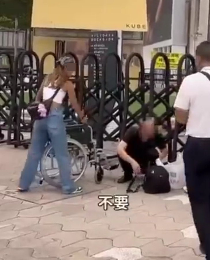 兩名香港網紅稱對很多遊客來到「踎低」感到不解,嘲諷他們是否腰骨有問題,手推輪椅往尖沙咀星光大道用普通話詢問多名蹲在地上的遊客:「我看你蹲了好久,是不是腰骨有問題,要不要坐輪椅?」(影片截圖)