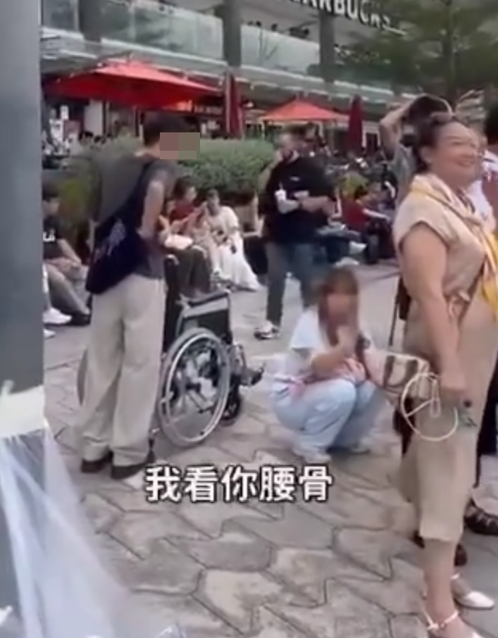 兩名香港網紅稱對很多遊客來到「踎低」感到不解,嘲諷他們是否腰骨有問題,手推輪椅往尖沙咀星光大道用普通話詢問多名蹲在地上的遊客:「我看你蹲了好久,是不是腰骨有問題,要不要坐輪椅?」(影片截圖)