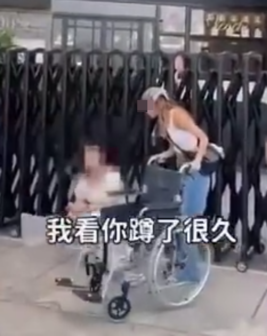 兩名香港網紅稱對很多遊客來到「踎低」感到不解,嘲諷他們是否腰骨有問題,手推輪椅往尖沙咀星光大道用普通話詢問多名蹲在地上的遊客:「我看你蹲了好久,是不是腰骨有問題,要不要坐輪椅?」(影片截圖)