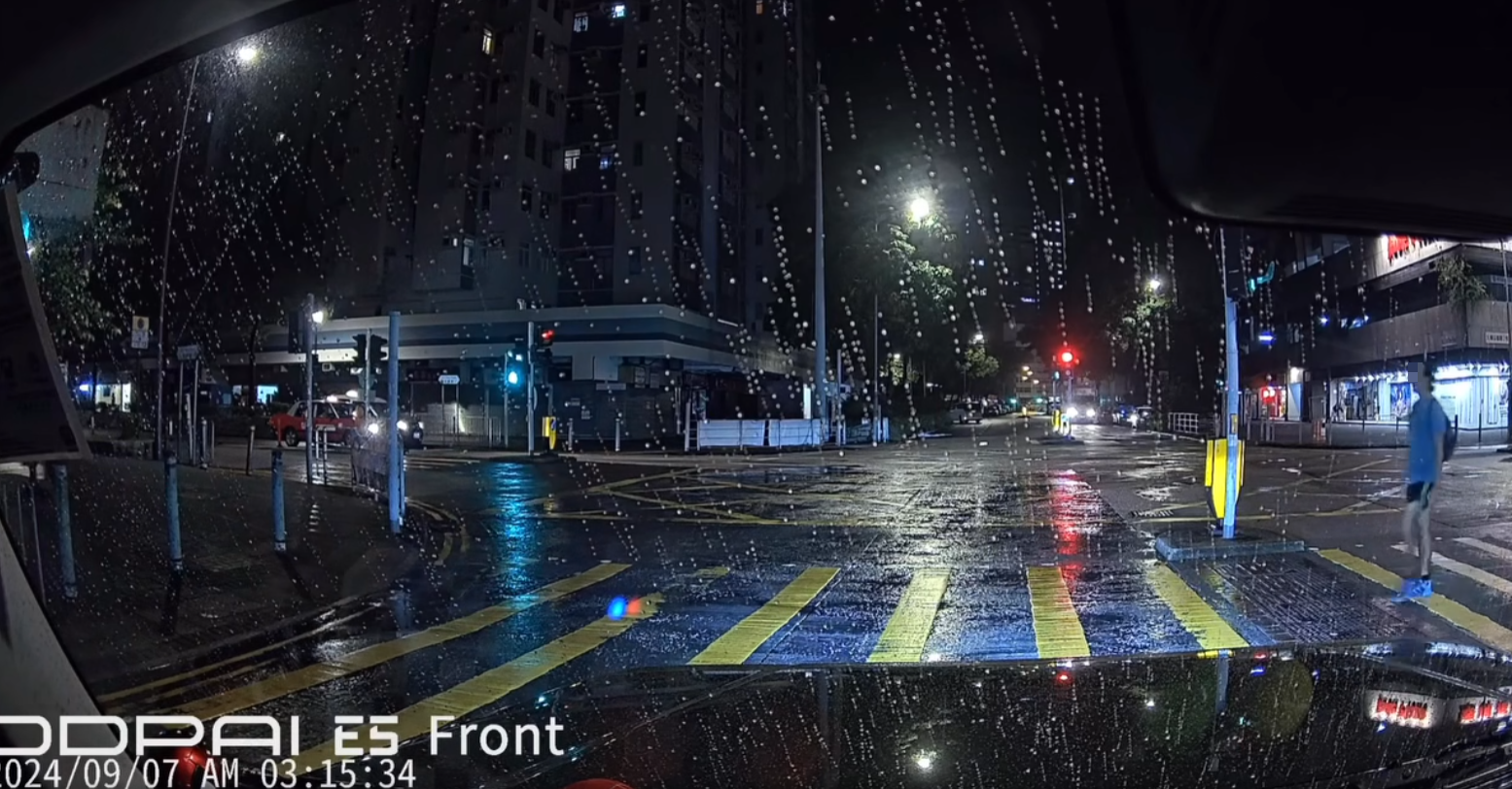 身穿淺藍衣短褲的背包中年男子由車頭右至左過馬路(facebook群組「大埔人大埔谷」)