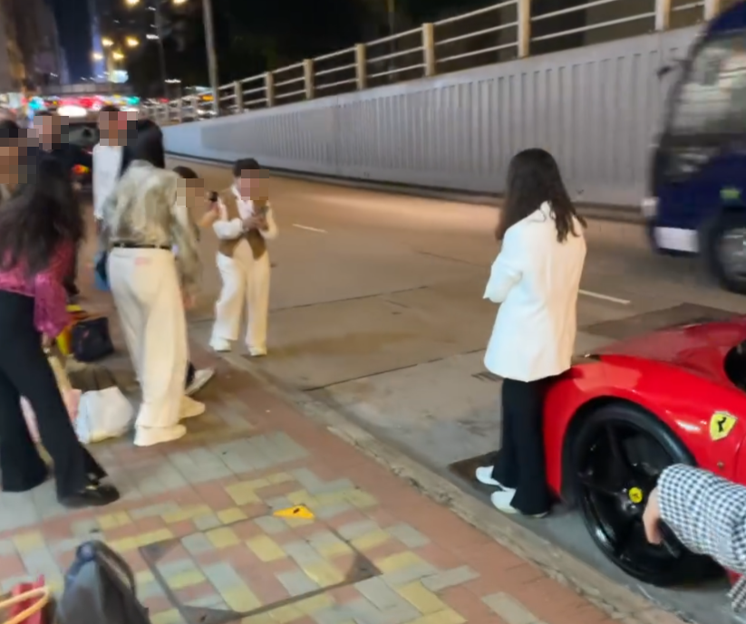 旺角亞皆老街街頭停泊一輛紅色法拉利,吸引不少內地大媽圍着打卡拍照,有人甚至半挨靠在車頭冚位置 (Threads影片截圖)