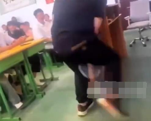 片中教師用力將羽毛球拍柄桶向學生屁股。(微博)