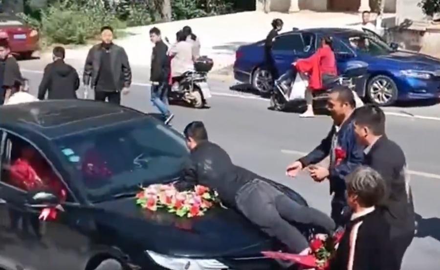 新娘哥哥卻追出去趴在禮車上,阻攔禮車離開,其後被人拉開。(微博)