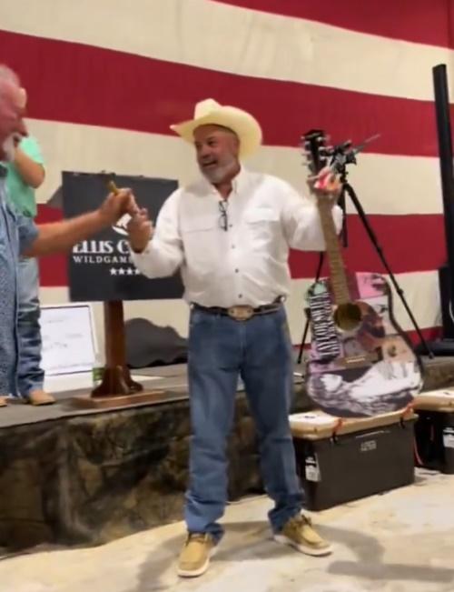 男子上台由主持人手中接過鐵鎚和結他後,隨即用鐵槌敲結他的琴身,現場則有群眾拍手叫好。(X)