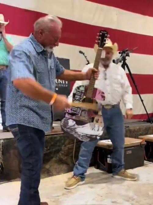 男子上台由主持人手中接過鐵鎚和結他後,隨即用鐵槌敲結他的琴身,現場則有群眾拍手叫好。(X)