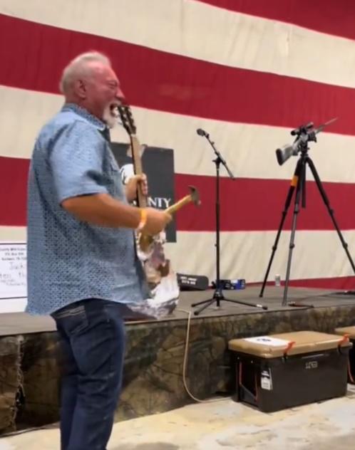 男子上台由主持人手中接過鐵鎚和結他後,隨即用鐵槌敲結他的琴身,現場則有群眾拍手叫好。(X)