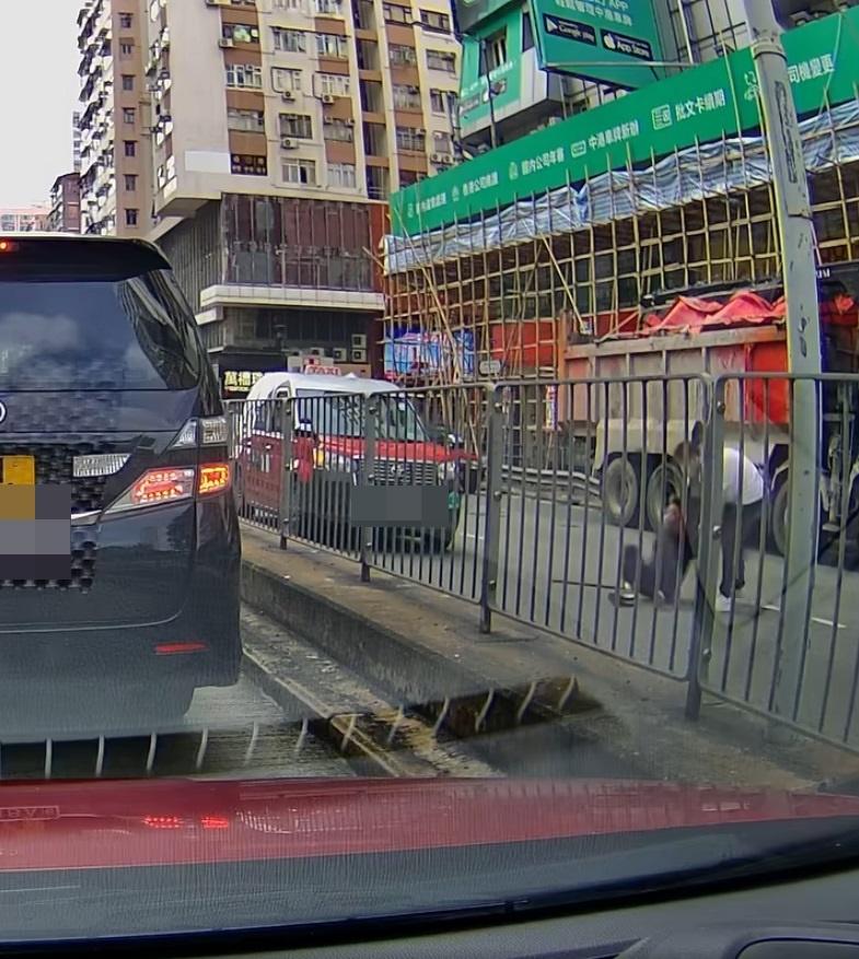 一名拿著拐杖的黑衣男子,坐在地上慢慢移出馬路。(網片截圖)