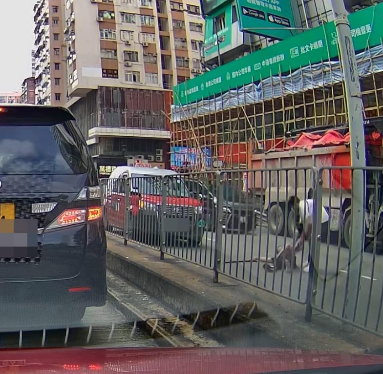 一名拿著拐杖的黑衣男子,坐在地上慢慢移出馬路。(網片截圖)