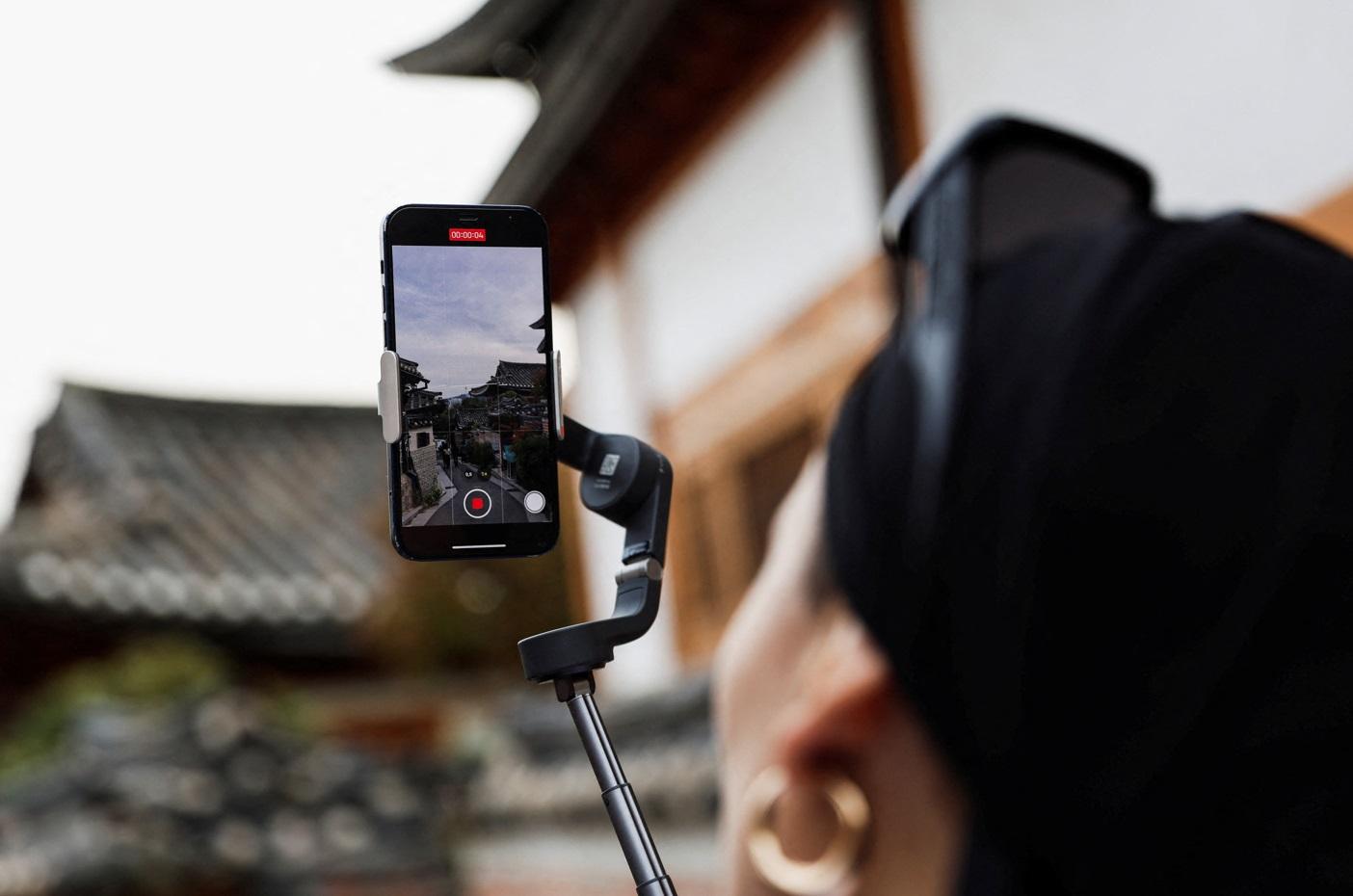 遊客用自拍神器拍攝村內景緻。(路透社)