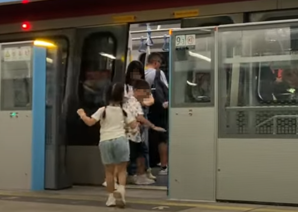 帶着一對仔女的母親於港鐵落馬洲站時情急衝門,惟她未有拖實二人,與緊跟其後的兒子及時進入車廂(影片截圖)