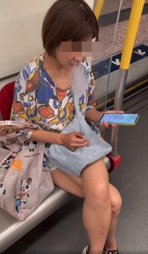 一名中年婦女坐在港鐵關愛座上,期間懷疑吸食電子煙,大模廝樣地吞雲吐霧。(網片截圖)