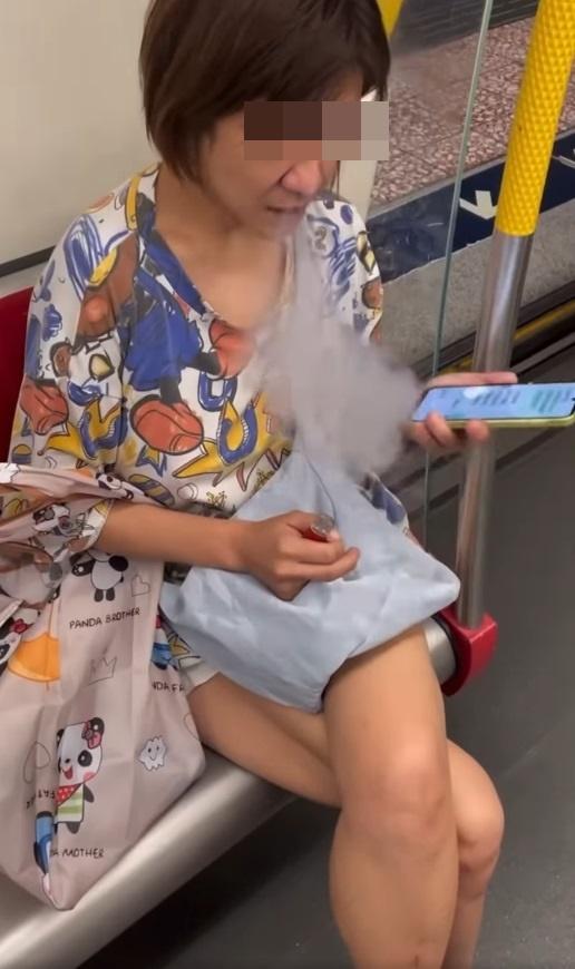 一名中年婦女坐在港鐵關愛座上,期間懷疑吸食電子煙,大模廝樣地吞雲吐霧。(網片截圖)