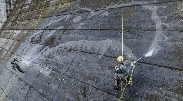 工作人員垂吊在岩屋川內水壩的壁面上先進行精確的點位標記,接著使用高壓水槍將邊緣勾勒出來。(X)