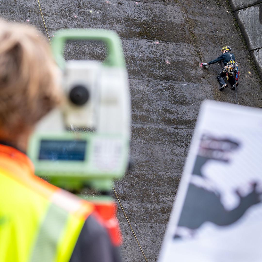 工作人員垂吊在岩屋川內水壩的壁面上先進行精確的點位標記,接著使用高壓水槍將邊緣勾勒出來。(X)