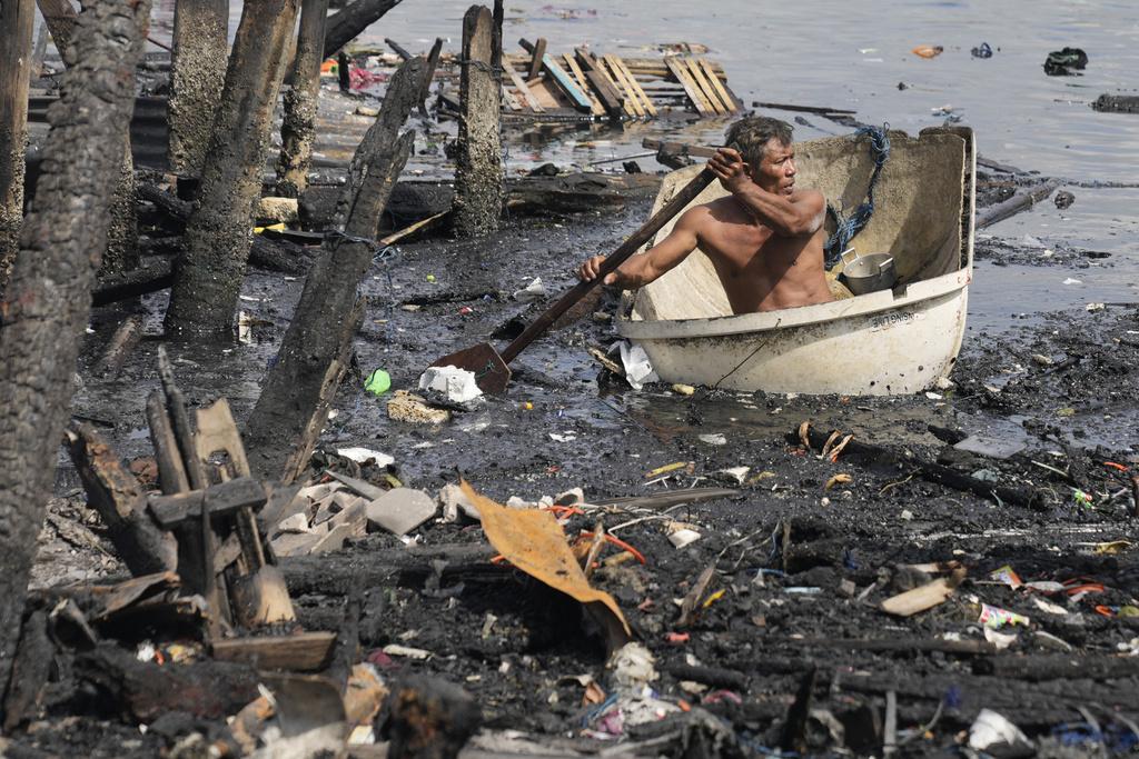 菲律賓首都馬尼拉貧民窟大火,居民乘坐臨時搭建的木筏逃走。(美聯社)