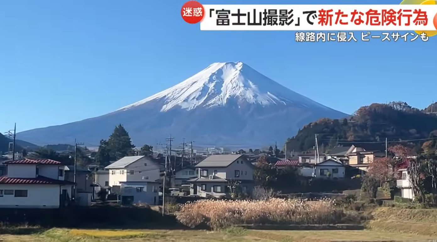 在富士急行線一處可以見到富士山的平交道中,有很多來自外國的旅客站在平交道旁打卡(影片截圖)