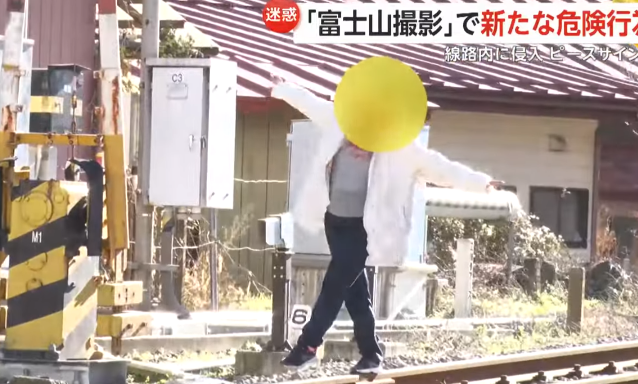 有女遊客站在路軌上拍攝時,平交道警報器已響起,有列車即將駛過,她隨即離開路軌,與另外兩名女子拖着行李箱前往另一區域。(影片截圖)