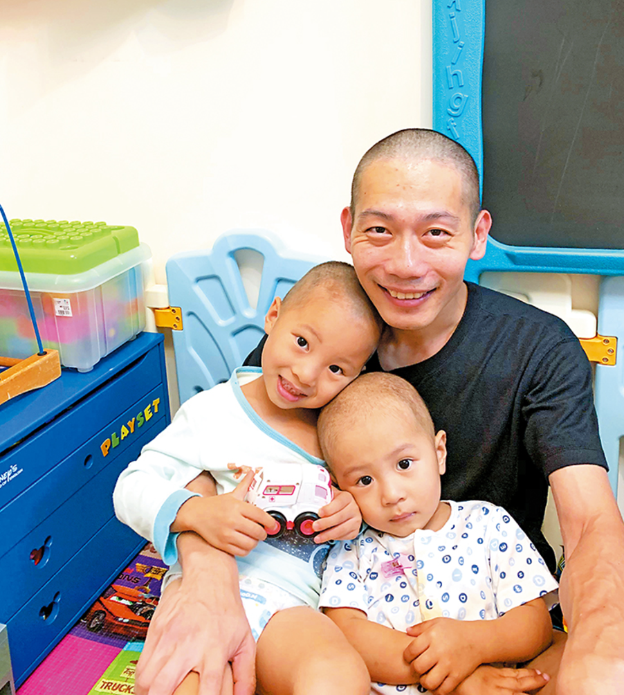 為鼓勵幼子丁丁積極抗癌,謙哥與其長子雙雙把頭髮剷光。(《警聲》圖片)