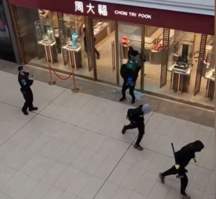 多倫多周大福遭6名劫匪搶走大量金飾珠寶,事發時有商場保安員在周大福門外眼白白看6名劫匪逃離現場,僅拍片取證沒有阻止。(影片截圖)
