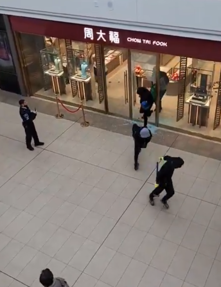 多倫多周大福遭6名劫匪搶走大量金飾珠寶,事發時有商場保安員在周大福門外眼白白看6名劫匪逃離現場,僅拍片取證沒有阻止。(影片截圖)