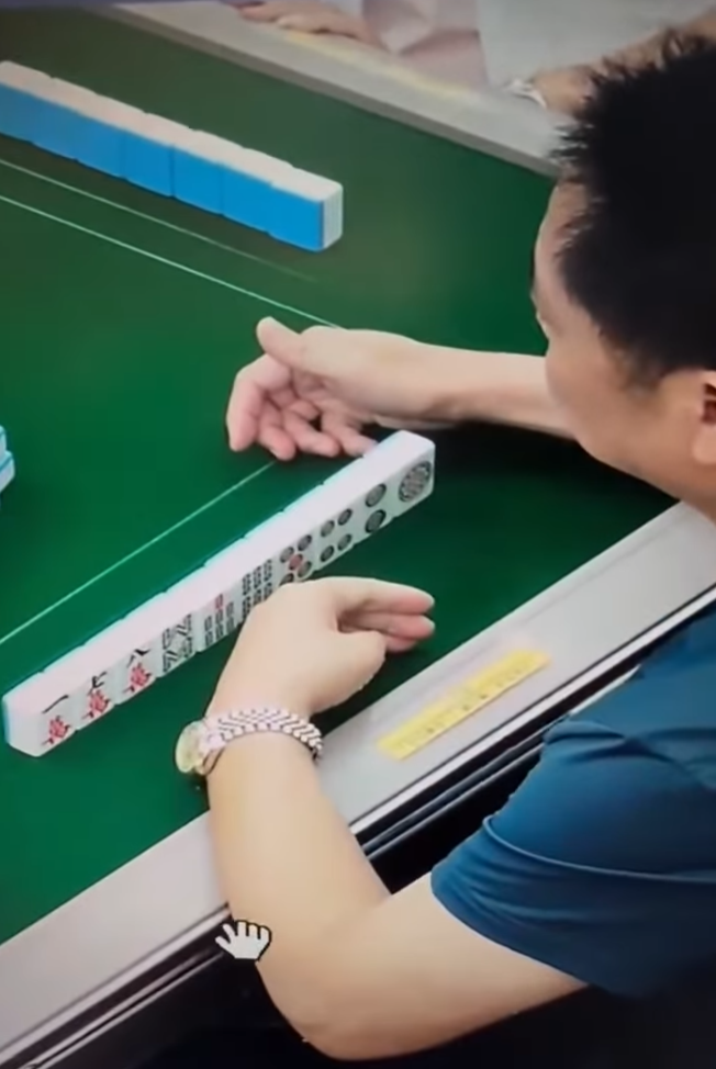 該段約42秒影片顯示一名中年男子在麻雀館打牌時,左手從口中拿出預先準備好的貼紙