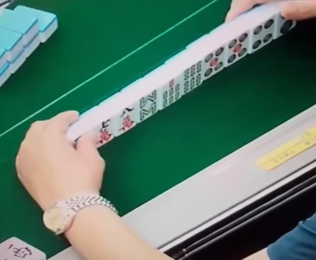 及後右手拿牌再出牌時,左手把貼紙貼在一隻雀麻牌之上,頓時令「一萬」變「六萬」