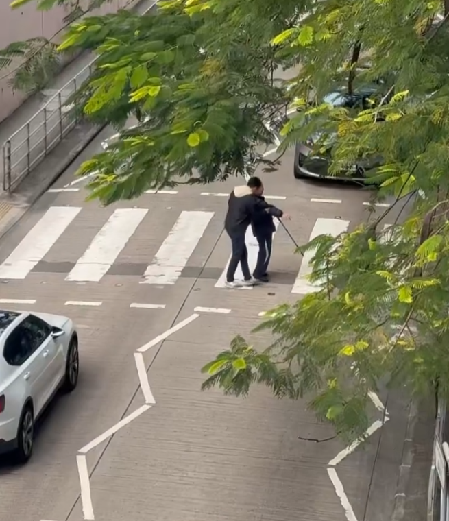 樂富一名司機主動落車攙扶一位持柺杖的老翁橫過斑馬線,兩線的車龍均耐心靜待(影片截圖)