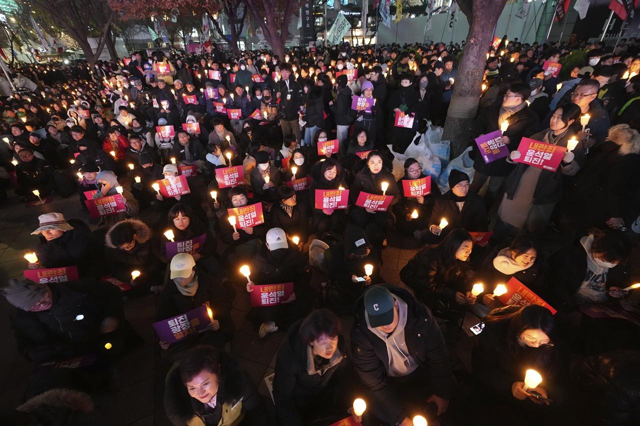 首爾市內多個地點,包括國會大樓和光化門廣場都有民眾舉起燭火示威集會,要求尹錫悅立即下台。(AP)