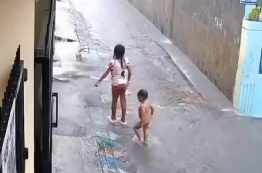 女童走到一處下水道旁,似乎發現這處積水特別多,就伸手指向下水道。(X)