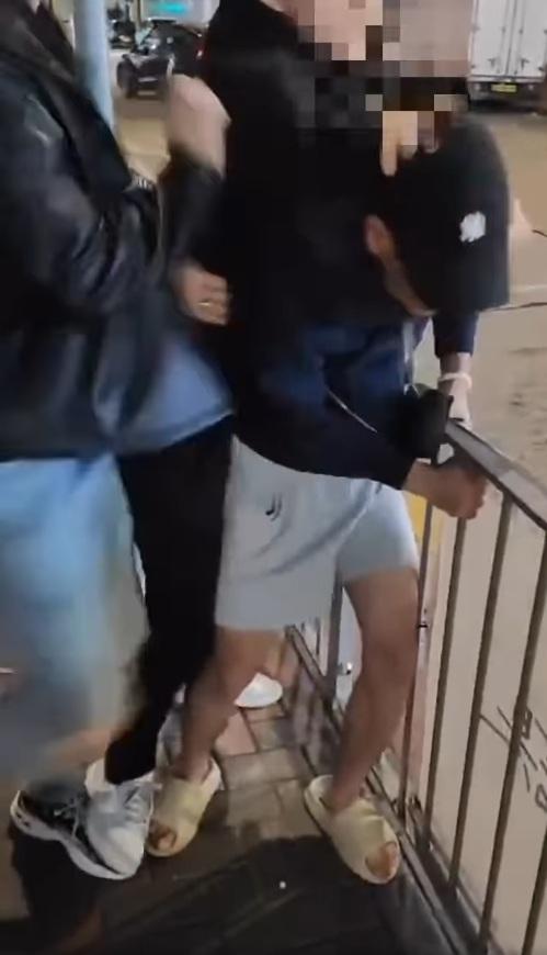 短褲男只能抓住鐵欄自保,不斷捱打。(網片截圖)