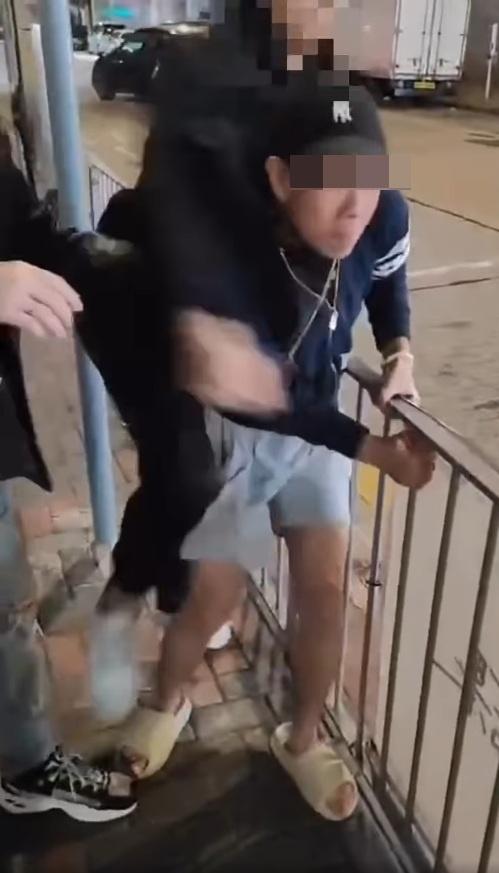 短褲男只能抓住鐵欄自保,不斷捱打。(網片截圖)