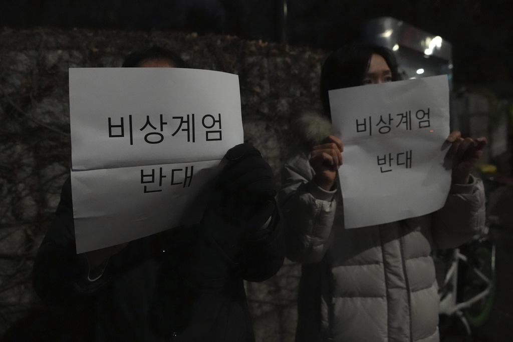 有民眾在國會外高舉反對實施緊急戒嚴令標語。(美聯社)