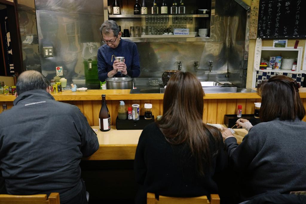 料理主理人用手感受清酒的溫度。(美聯社)