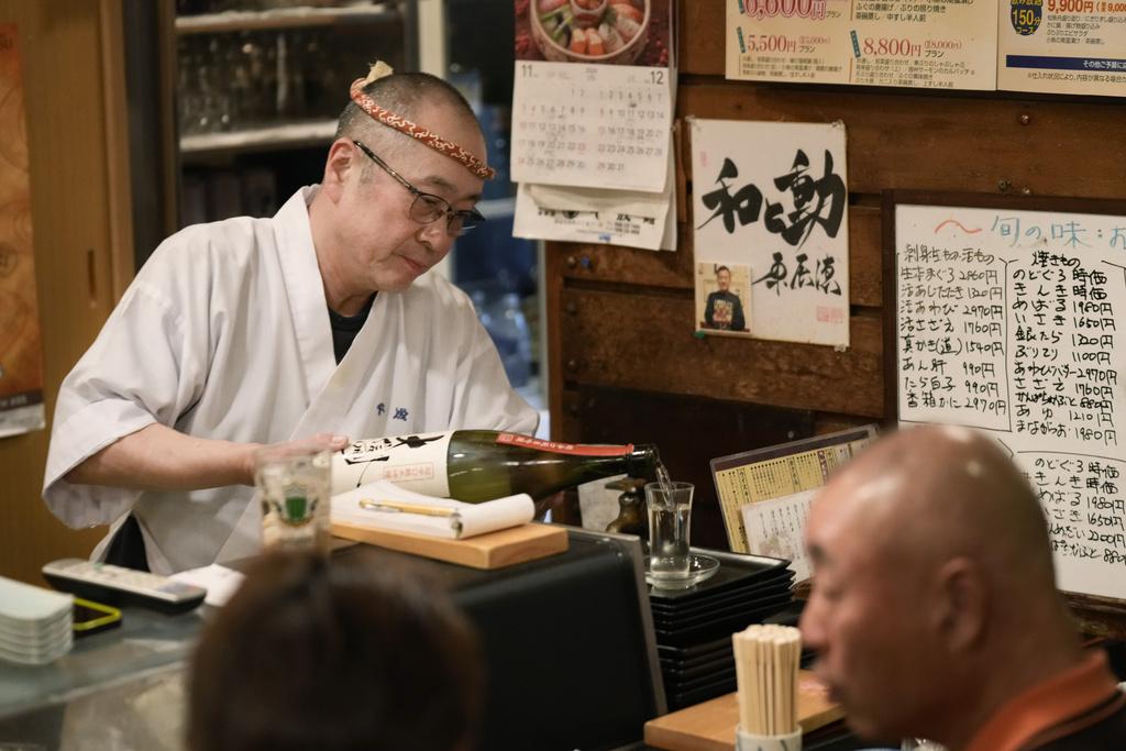 廚師向客人奉上清酒。(美聯社)