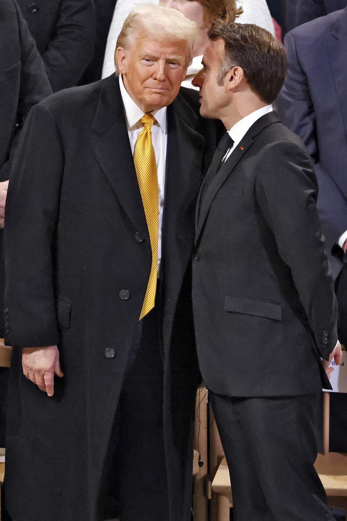 在聖母院重開儀式上,馬克龍與特朗普「咬耳仔」。(美聯社)