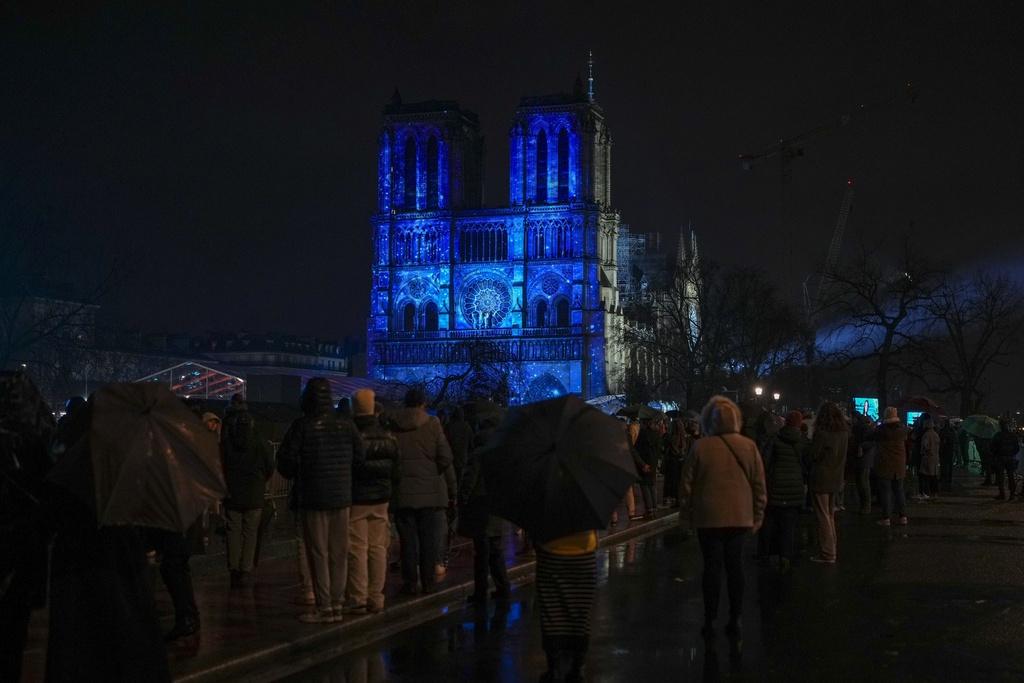 幻彩光影投射在聖母院正立面牆上,市民冒雨欣賞。(美聯社)